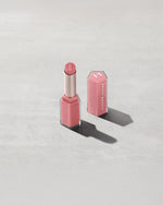 Open product shot of Gloss Bomb Stix Shimmer in shade Fussy on a concrete background.
