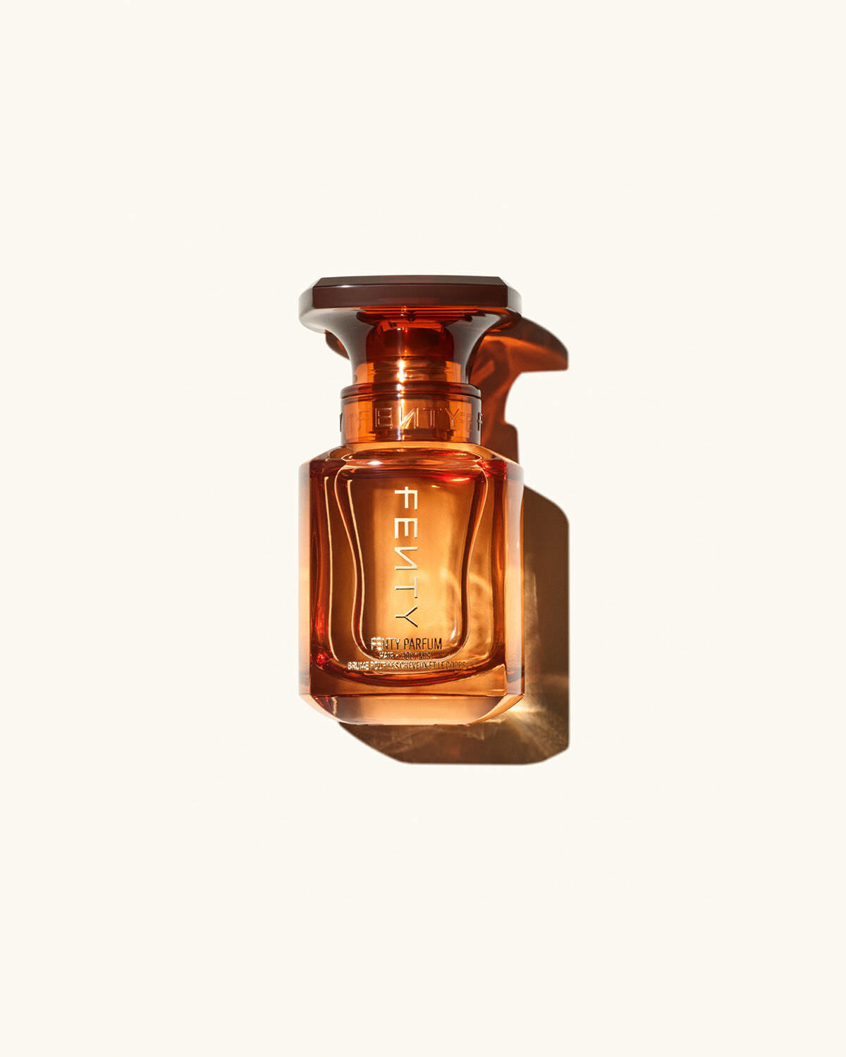 Fenty Parfum Hair + Body Mist on a cream background.
